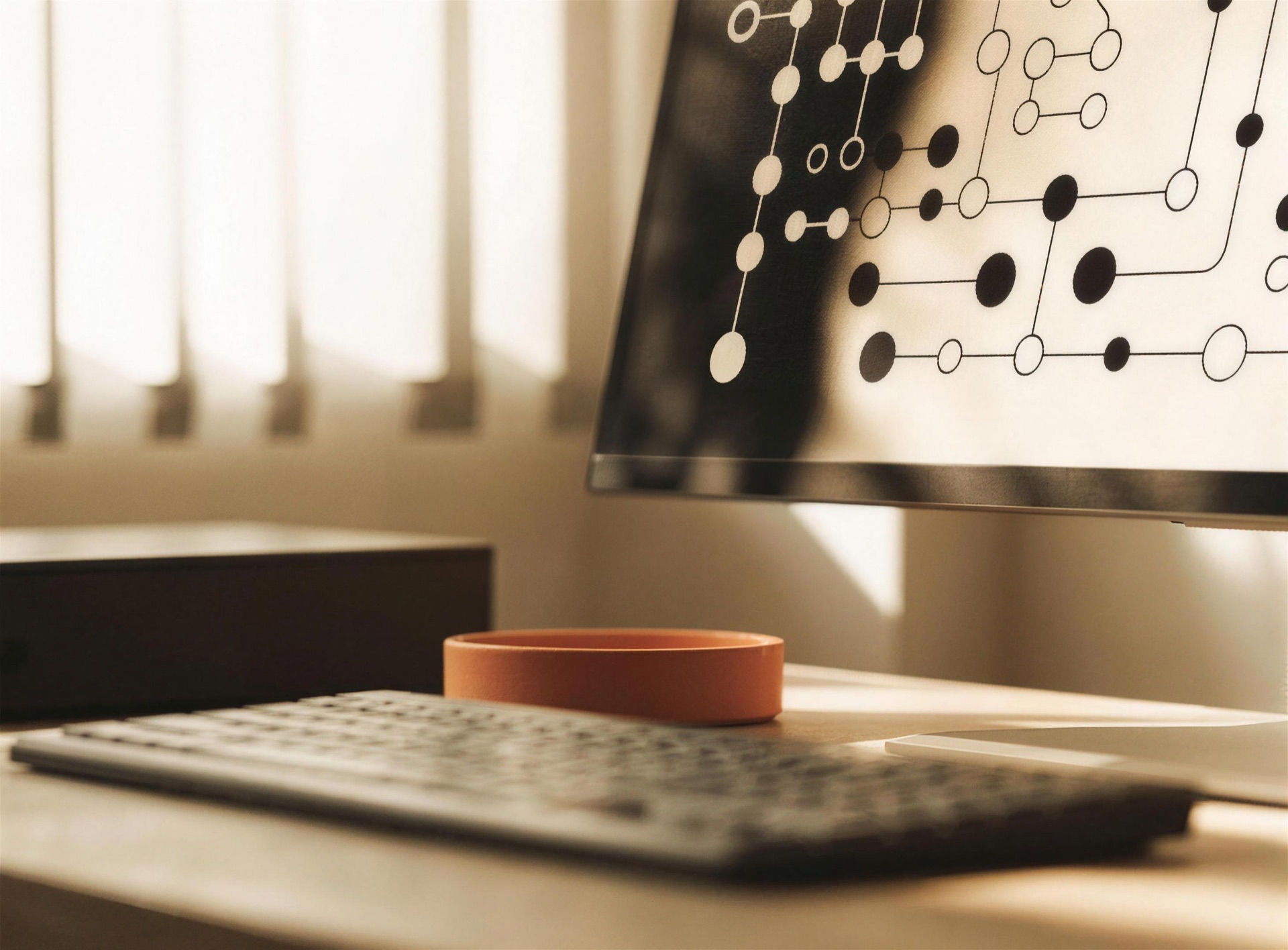 A studio desk with an automation dataflow diagram on screen, lit by warm window light